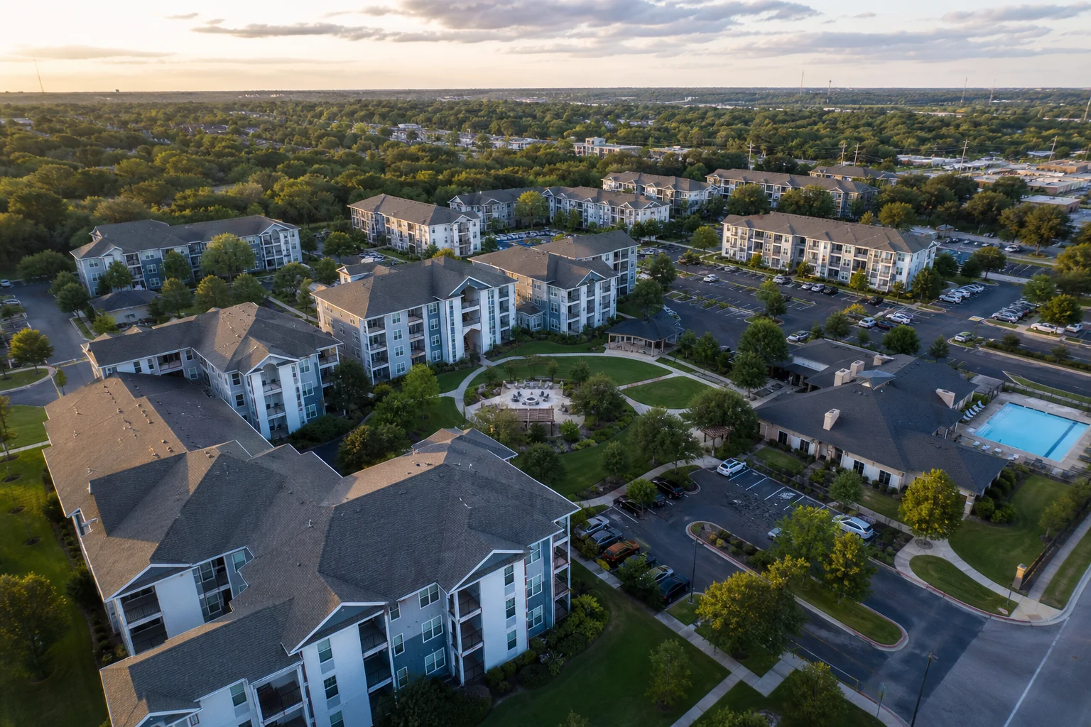 Aerial view of a mid-rise apartment community with landscaped courtyards and surface parking